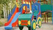 Happy boy swinging in toy car on children playground.