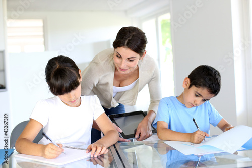 Photo: Teacher and kids in classroom writing on notebook Teacher and kids in classroom writing on notebook