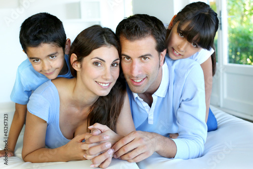 Photo: Portrait of happy family laying down bed Portrait of happy family laying down bed