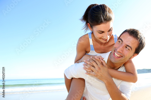 Foto: Man carrying girlfriend on his back at the beach Man carrying girlfriend on his back at the beach
