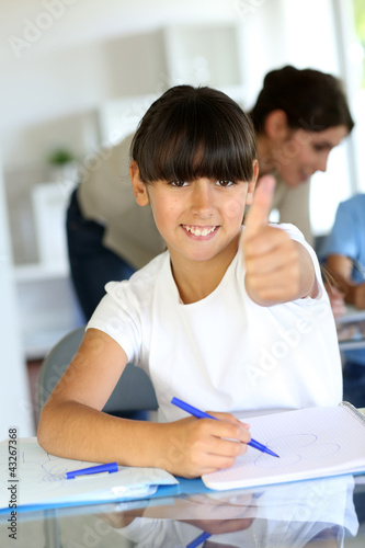 Foto: Closeup of little girl in class showing thumb up Closeup of little girl in class showing thumb up