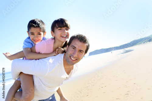 Foto: Daddy carrying children on his back at the beach Daddy carrying children on his back at the beach
