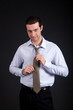 Businessman adjusting his collar on a dark background