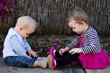 Baby boy and toddler girl sitting and playing outdoors