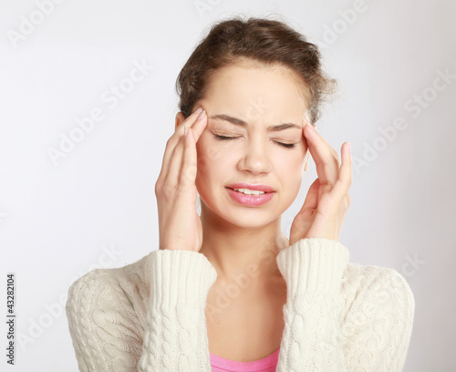 Photo: A young woman with a headache holding head A young woman with a headache holding head