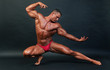 Bodybuilder posing on dark background.