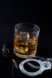 Whiskey on the rocks with car key and handcuff