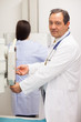 Doctor checking a machine while a patient is having a mammograph