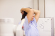 Patient placing her arms on her head while standing in front of