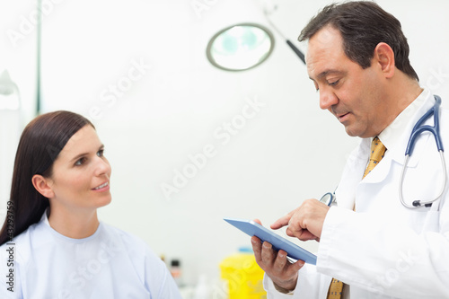 Photo: Doctor talking with a patient while using a tablet Doctor talking with a patient while using a tablet