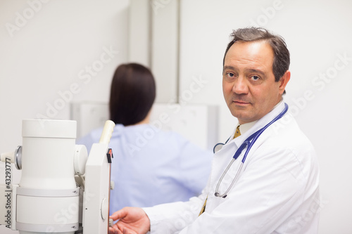 Foto: Doctor checking a machine while a patient is having a mammograph Doctor checking a machine while a patient is having a mammograph