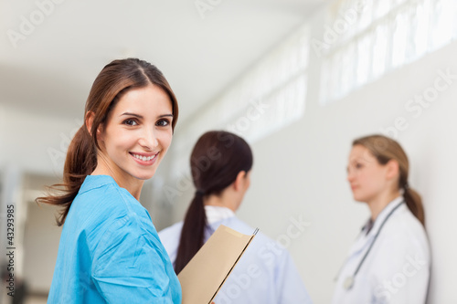 Photo: Smiling nurse while standing in a hallway with a patient and a Smiling nurse while standing in a hallway with a patient and a