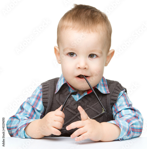 Photo: Cute little child is biting glasses Cute little child is biting glasses