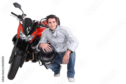 Photo: Man crouching next to motorcycle Man crouching next to motorcycle