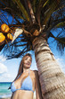 Foto: Young woman relaxing under the palm tree. Vertical shot. Young woman relaxing under the palm tree. Vertical shot.