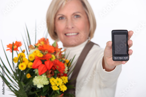 Photo: Elderly florist holding flowers and mobile telephone Elderly florist holding flowers and mobile telephone