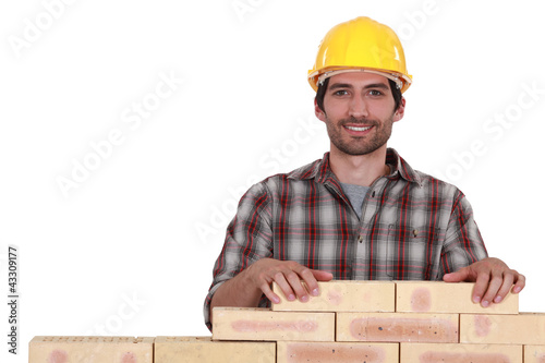 Foto: Man building brick wall Man building brick wall