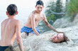 Two teenage boys covering with sand teenage girl on beach
