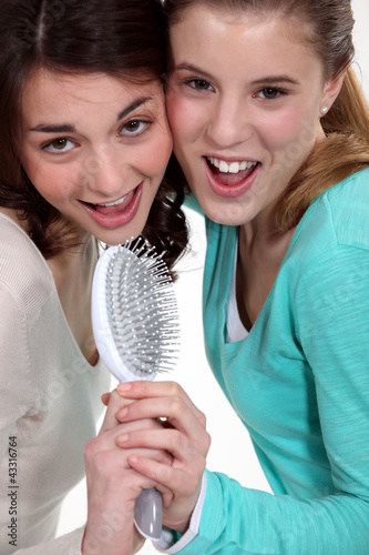 Photo: Two teenagers singing with a brush. Two teenagers singing with a brush.