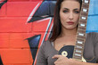 Girl with guitar in front of painted wall