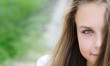 Portrait of half face beautiful young woman on green background.