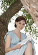 Foto: young girl sitting on a tree and reading a book young girl sitting on a tree and reading a book