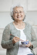 Senior Asian woman eating Asian food with chopsticks