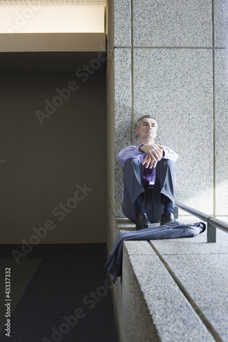 Photo: Caucasian businessman relaxing on office ledge Caucasian businessman relaxing on office ledge