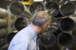 Caucasian foreman looking at pipes in factory