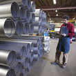 Mixed race worker standing near pipes in factory