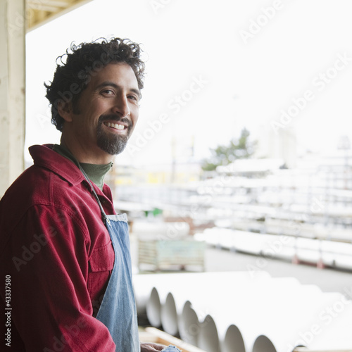 Photo: Mixed race worker standing on factory loading dock Mixed race worker standing on factory loading dock