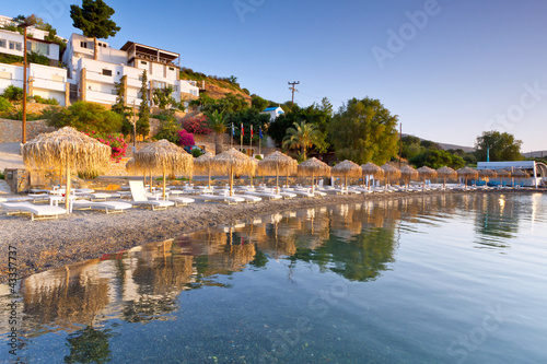 Foto: Sunbeds with parasols at Mirabello Bay on Crete, Greece Sunbeds with parasols at Mirabello Bay on Crete, Greece