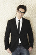 Trendy Caucasian businessman leaning against wall