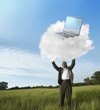 Black businessman holding laptop on cloud in field