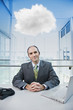 Caucasian businessman sitting at desk with cloud over his head