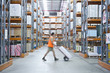Worker pushing hand truck in warehouse