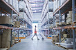Worker pushing hand truck in warehouse