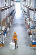 Worker standing with hand truck in warehouse