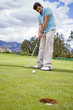 Hispanic man putting golf ball