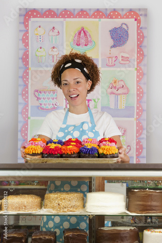 Photo: Black baker holding tray of cupcakes Black baker holding tray of cupcakes