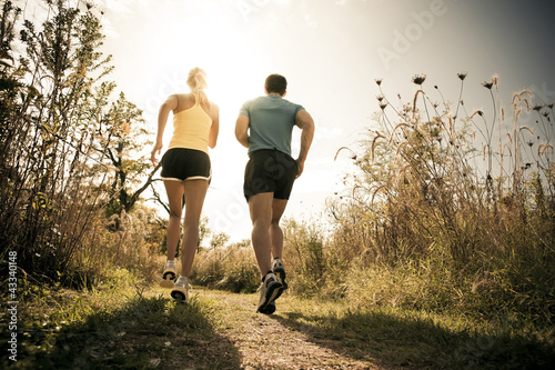 Photo: Caucasian couple running together on path Caucasian couple running together on path