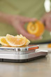 Senior woman weighing orange on scale