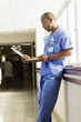Black doctor looking at medical chart in hospital