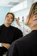 Hispanic woman looking at reflection in beauty salon