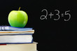 Photo: Addition equation written on a blackboard, books and apple Addition equation written on a blackboard, books and apple