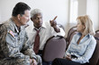 Soldier sitting in chair talking to business people