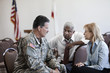 Soldier sitting in chair talking to business people
