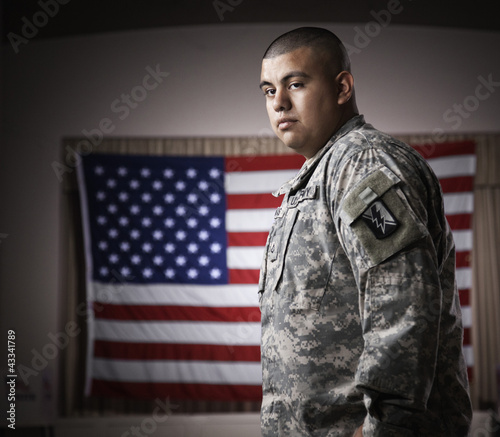 Photo: Hispanic soldier standing in front of American flag Hispanic soldier standing in front of American flag