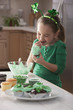 Caucasian girl making St. Patrick's cupcakes