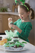 Caucasian girl making St. Patrick's cupcakes